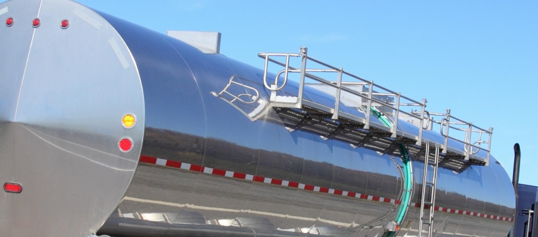Polished insulated stainless tank barrel with catwalk and railing against a clear sky